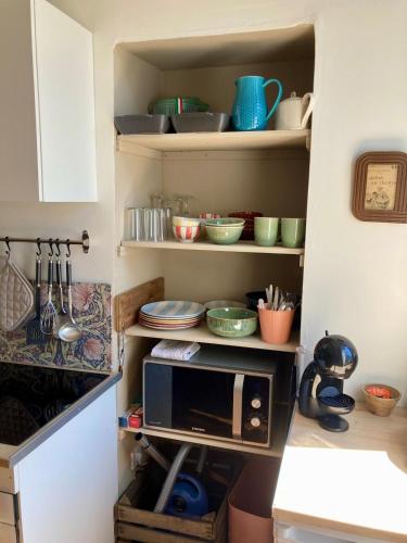 a kitchen with a microwave and some dishes on shelves at L Henri in Oloron-Sainte-Marie