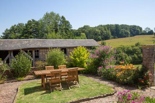 a wooden table and chairs in a garden at La Daubinière in Saint-Ouen-le-Pin