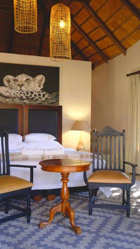 a bedroom with a bed and a table and chairs at Mologa River Lodge in Rust de Winter