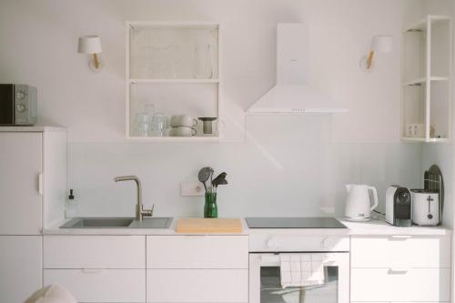 a white kitchen with white cabinets and a sink at Well M cottage in Velem