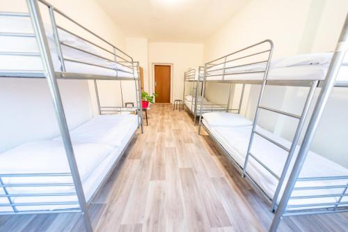 a room with three bunk beds and a wooden floor at Party Hostel Králíkárna in Mikulov