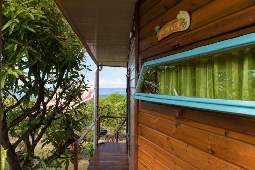 a wooden house with a window with a view of the ocean at Bungalow Pointe Châteaux St Leu ocean view, pool in Saint-Leu