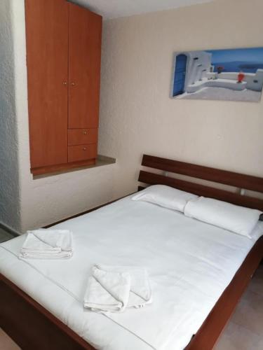 a bedroom with a bed with white sheets and a cabinet at Kapsochora blue in Pefkohori