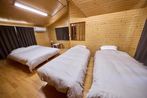 two beds in a room with wooden walls at WATERSIDE Base 鹿嶋 北浦 in Kashima