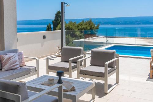 a patio with two chairs and a table and a pool at Luxurious VILLA LAPIS - heated pool, sauna, gym and spa, 120m to sandy beach in Omiš