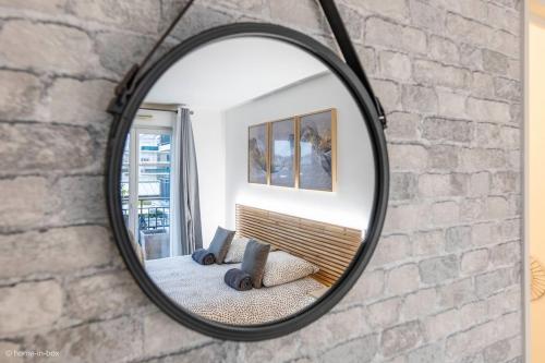 un miroir suspendu sur un mur en briques avec un canapé dans l'établissement Le Petit Bussy, 4 pers Disneyland Paris 10min, à Bussy-Saint-Georges