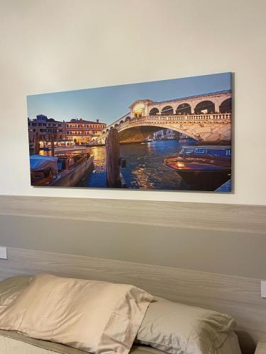 a painting of a bridge on a wall above a bed at Casa sulla Laguna CASTELLO in Venice