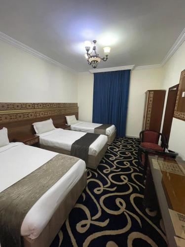 a hotel room with two beds and a chair at Sultan awtadHotel فندق اوتاد السلطان العزيزية in Makkah