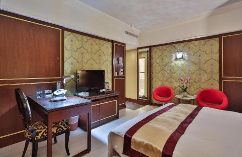 a hotel room with a bed and a desk and two red chairs at MILORD BOUTIQUE HOTEL in Kaohsiung