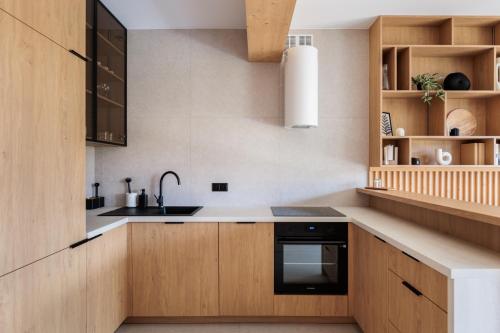 a kitchen with wooden cabinets and a sink at Stylchyn Park - Czorsztyn Exclusive - by Upstairs in Kluszkowce
