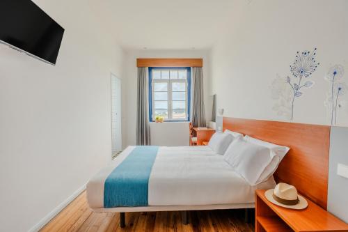 a hotel room with a bed and a television at Spirit Hotel Fonte Real - Antigo Hotel Flora in Monte Real