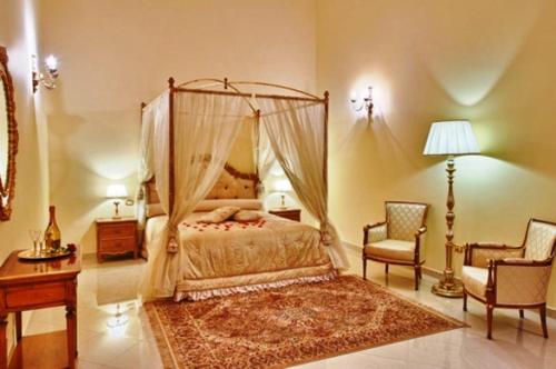 a bedroom with a canopy bed and a chair at Castello Conti Filo in Torre Santa Susanna