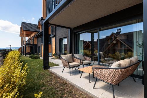 a patio with chairs and a table and windows at Stylchyn Park - Czorsztyn Exclusive - by Upstairs in Kluszkowce