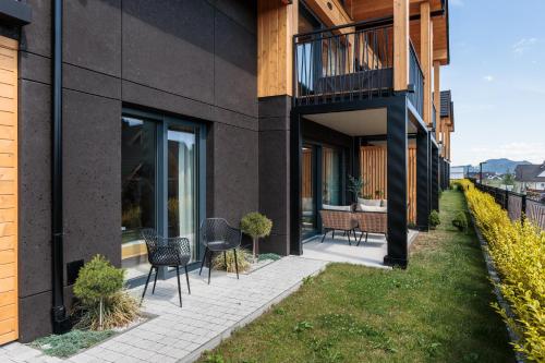a patio with chairs and tables on the side of a building at Stylchyn Park - Czorsztyn Exclusive - by Upstairs in Kluszkowce