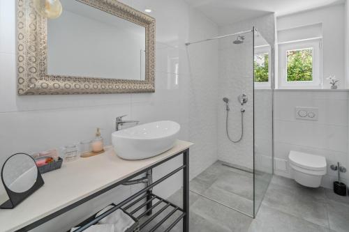 a white bathroom with a sink and a shower at Luxurious VILLA LAPIS - heated pool, sauna, gym and spa, 120m to sandy beach in Omiš