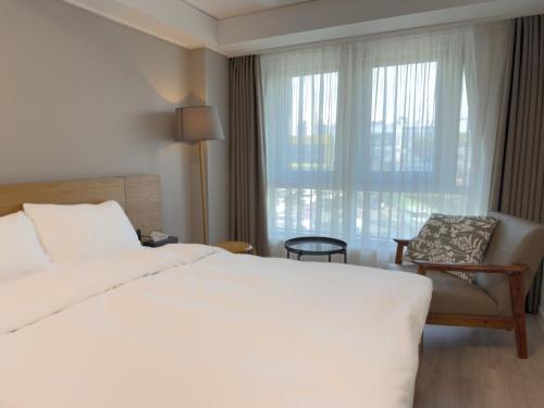 a bedroom with a bed and a chair and a window at Sokcho Marina Hotel in Sokcho