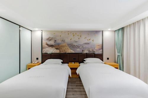 a row of three beds in a room at GreenTree Alliance Jiangsu Nanjing Pukou District Zhongsheng Street Wende Road Metro Station Hotel in Pukou