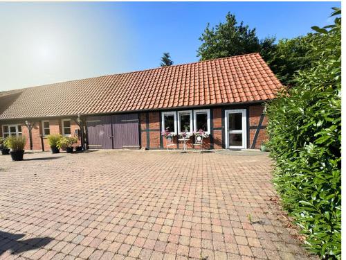 a brick house with a red roof and a brick driveway at "Grüne Oase" in der Lüneburger Heide in Altenmedingen