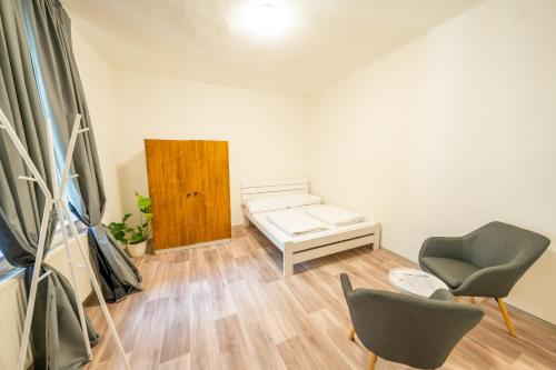 a living room with a bed and two chairs at Party Hostel Králíkárna in Mikulov