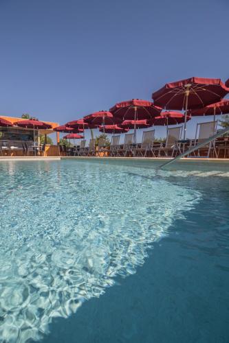 a pool of water with umbrellas and chairs at Camping Girasole in Girasole
