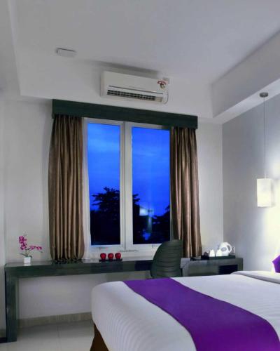 a hotel room with a bed and a window at Quest Hotel Balikpapan by ASTON in Balikpapan