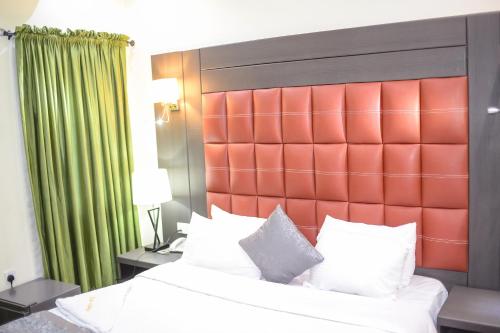 a bedroom with a large bed with a red headboard at Mainstay Luxury Hotel in Ibadan
