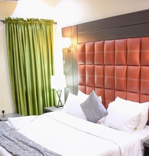 a bedroom with a large bed with a red headboard at Mainstay Luxury Hotel in Ibadan