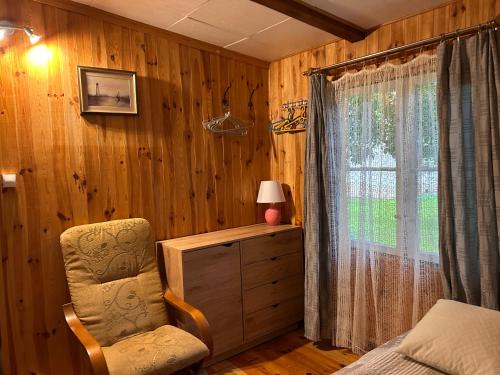 a bedroom with a bed and a chair and a window at Domek Letni Bałtycka in Sopot