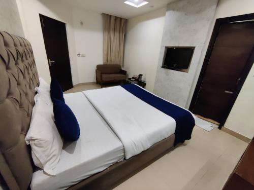 a bedroom with a bed and a chair and a television at Hotel Landmark in Chandīgarh