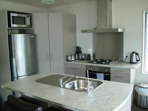a kitchen with a sink and a stainless steel refrigerator at Lawrence Townhouse Accommodation 18A in Lawrence