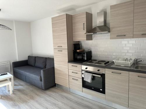 a kitchen with a couch and a stove top oven at Appartement neuf en centre ville de Libourne in Libourne