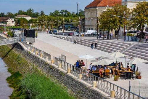 a group of people sitting at tables with umbrellas at Appartement neuf en centre ville de Libourne in Libourne