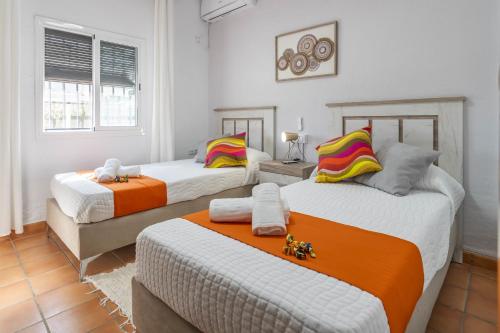 una camera con 2 letti arancioni e bianchi di Casa rural Buhaira a La Puebla de Cazalla