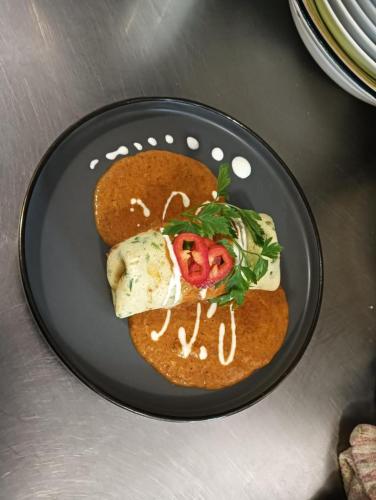 a black plate with a burrito with sauce on it at PENSIUNE RESTAURANT OVIDIU in Valea lui Mihai
