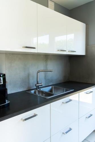 a kitchen with white cabinets and a sink at -Duinhuisje - voor families & honden nabij strand in Noordwijk