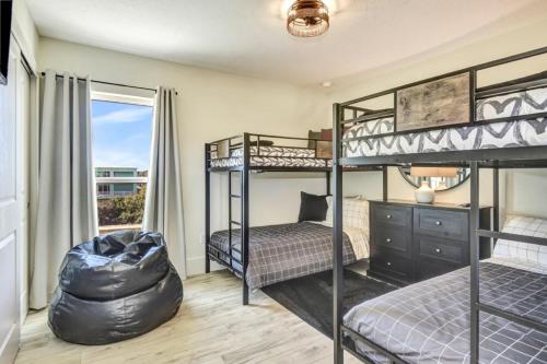 a bedroom with two bunk beds and a chair at The White House on Flagler Beach - Unit 23 in Flagler Beach