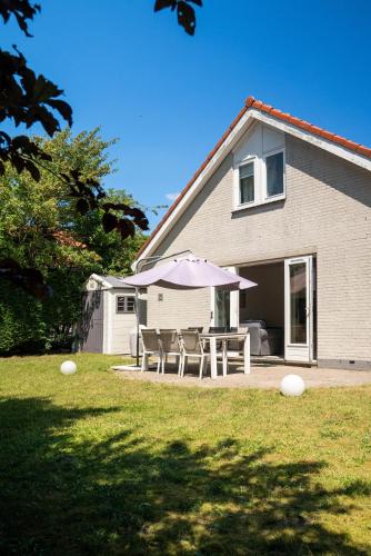 a house with tables and umbrellas in a yard at -Duinhuisje - voor families & honden nabij strand in Noordwijk