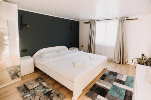 a bedroom with a white bed and a green wall at Szépasszony Guest House in Vlăhiţa