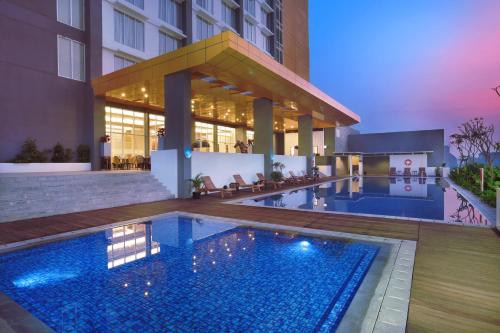 a swimming pool in front of a building at ASTON Banua Banjarmasin Hotel & Convention Center in Banjarmasin
