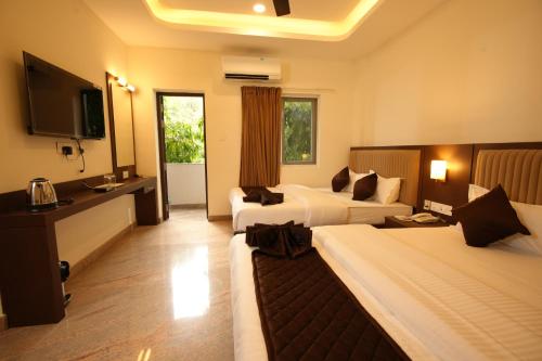 a hotel room with two beds and a television at Jsm Residency Egmore in Chennai