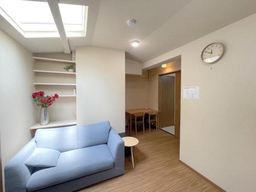 a living room with a blue couch and a clock at シェアホ天下茶屋 in Osaka