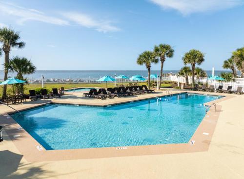 a swimming pool with chairs and the ocean in the background at 174 Beach Club Villa in Fripp Island