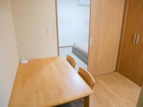a room with a wooden table and chairs and a bed at シェアホ天下茶屋 in Osaka