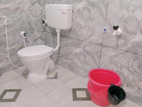 a bathroom with a toilet and a red bucket at GM Residency Beach Inn in Velankanni