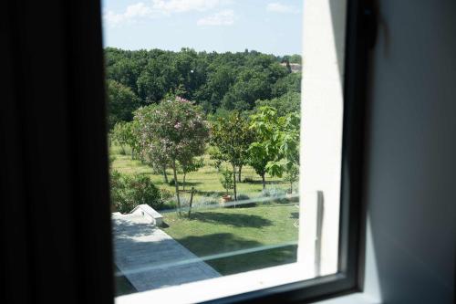 une fenêtre avec vue sur un champ d'arbres dans l'établissement Domaine de la Peyrine - Suite Huppe, à Carignan