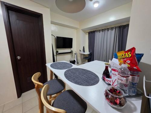 a kitchen with a white table with chairs and food on it at Pioneerwoodlands Mandaluyong Studio Unit in Manila