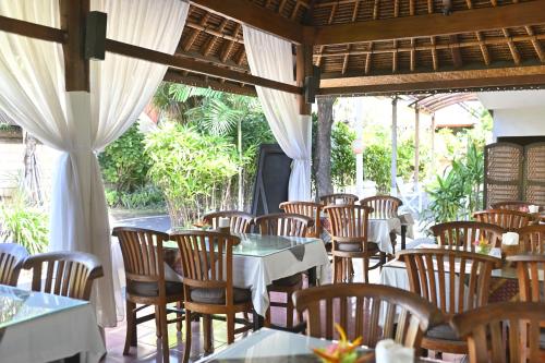 a restaurant with tables and chairs in a room at Puri Dewa Bharata Hotel & Villas in Legian