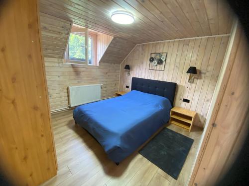 Un pequeño dormitorio con una cama azul en una habitación de madera en Vila Dani&Marina, en Porumbacu de Sus