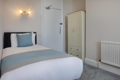 a white bedroom with a bed and a cabinet at The Cumberland Hotel in Eastbourne
