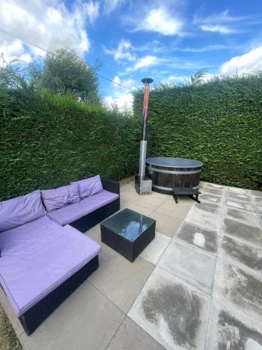 a patio with a couch and a fire place at Pine Lodge Posh Glamping With Wood Fired Hot Tub & Big Lincolnshire Skies in Wigtoft